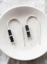 Pair of earrings with black beads on a white plate