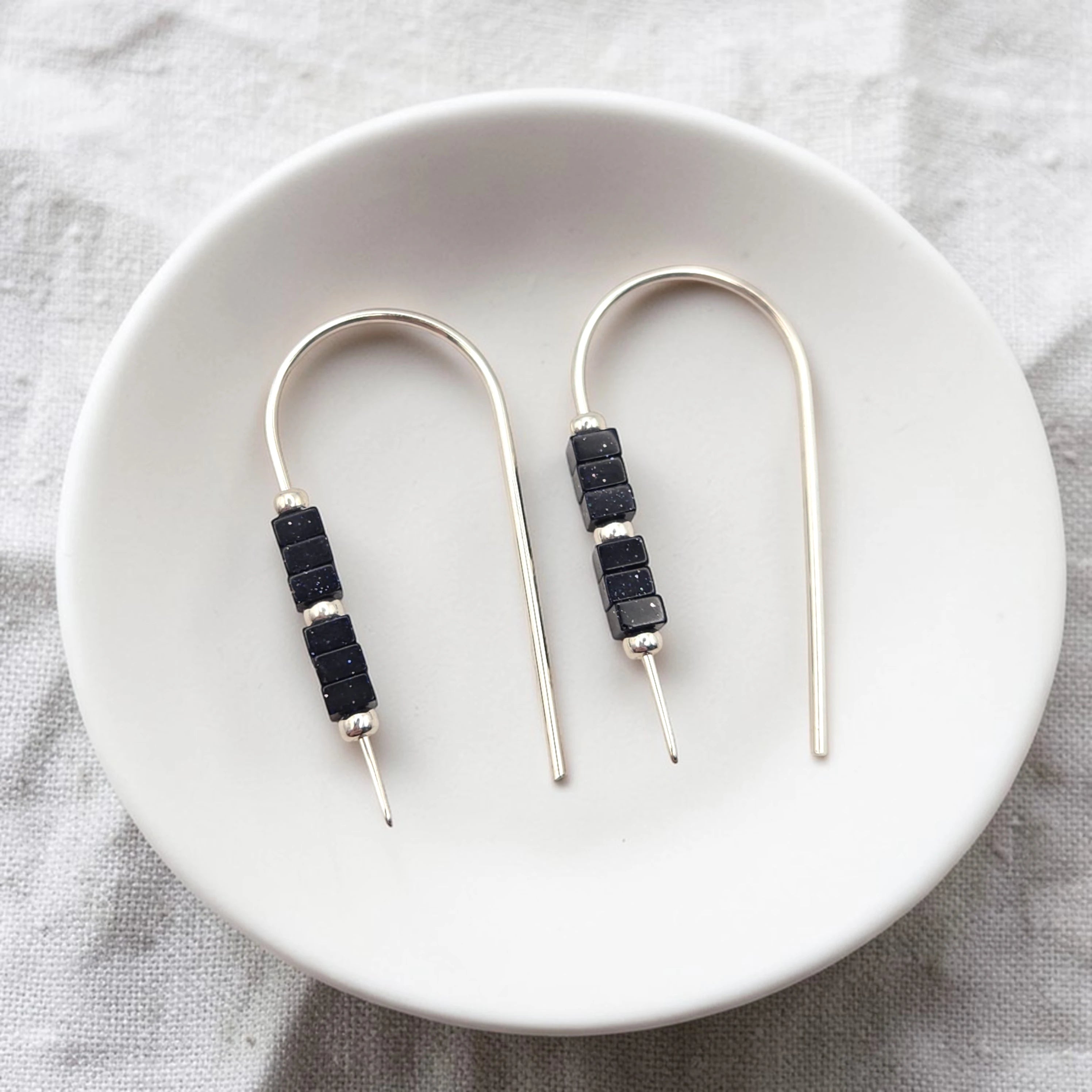Pair of earrings with black beads on a white plate