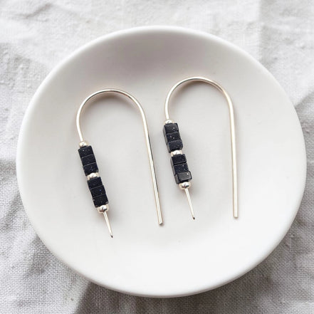 Pair of earrings with black beads on a white plate