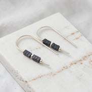 Silver earrings with black beads on a marble surface