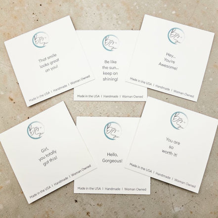 Set of six white cards with printed messages and a logo on a textured surface