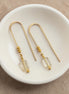 Gold earrings with citrine beads on a white dish