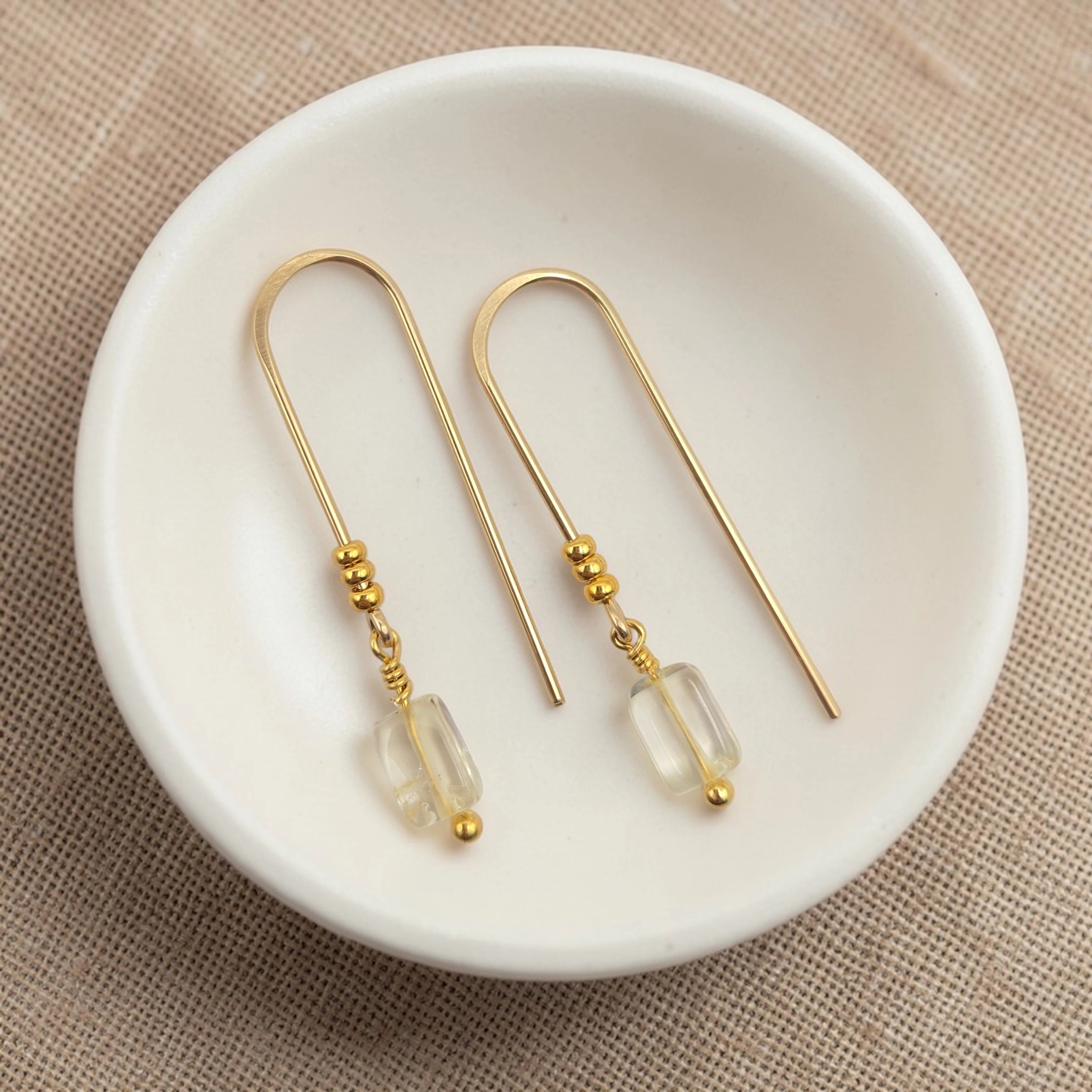 Gold earrings with citrine beads on a white dish