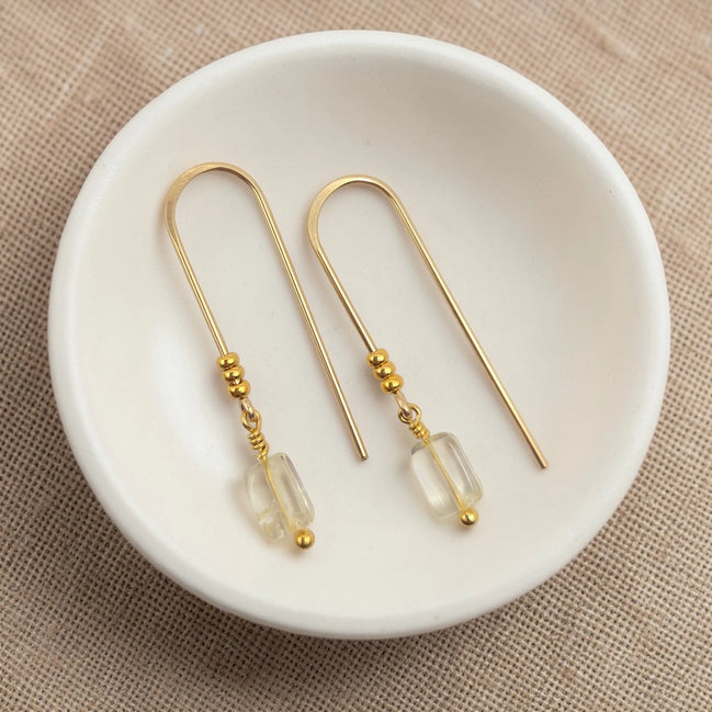 Gold earrings with citrine beads on a white dish