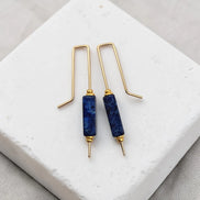 Pair of blue stone earrings with gold hooks on a white surface