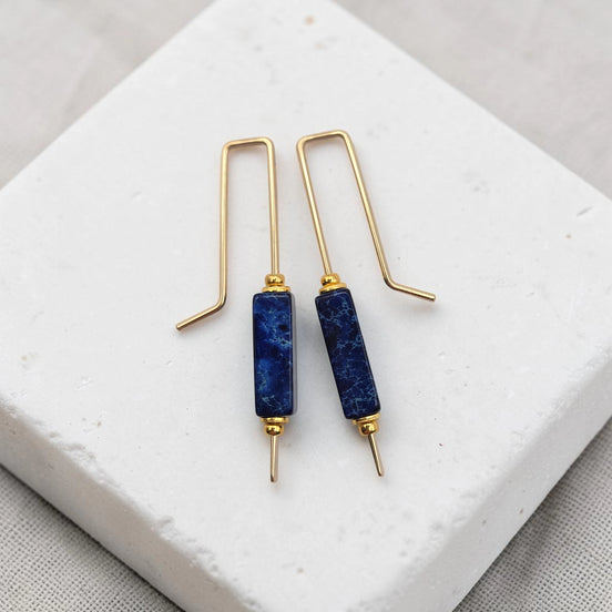 Pair of blue stone earrings with gold hooks on a white surface