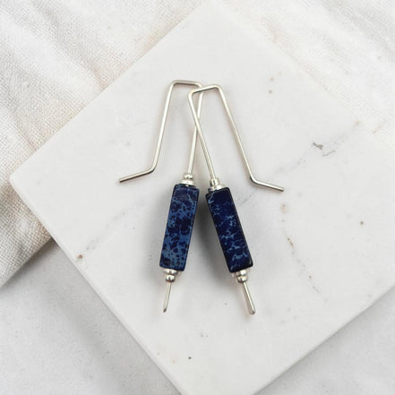 Blue stone earrings on a marble surface