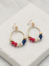 Gold hoop earrings with red white and blue beads on a white surface