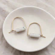 Pair of earrings with marble-like beads on a white dish