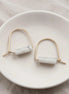 Pair of earrings with marble-like beads on a white dish