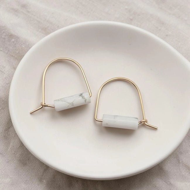 Pair of earrings with marble-like beads on a white dish