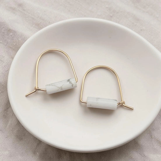 Pair of earrings with marble-like beads on a white dish