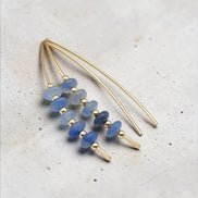 Gold and blue beaded earrings on a textured surface
