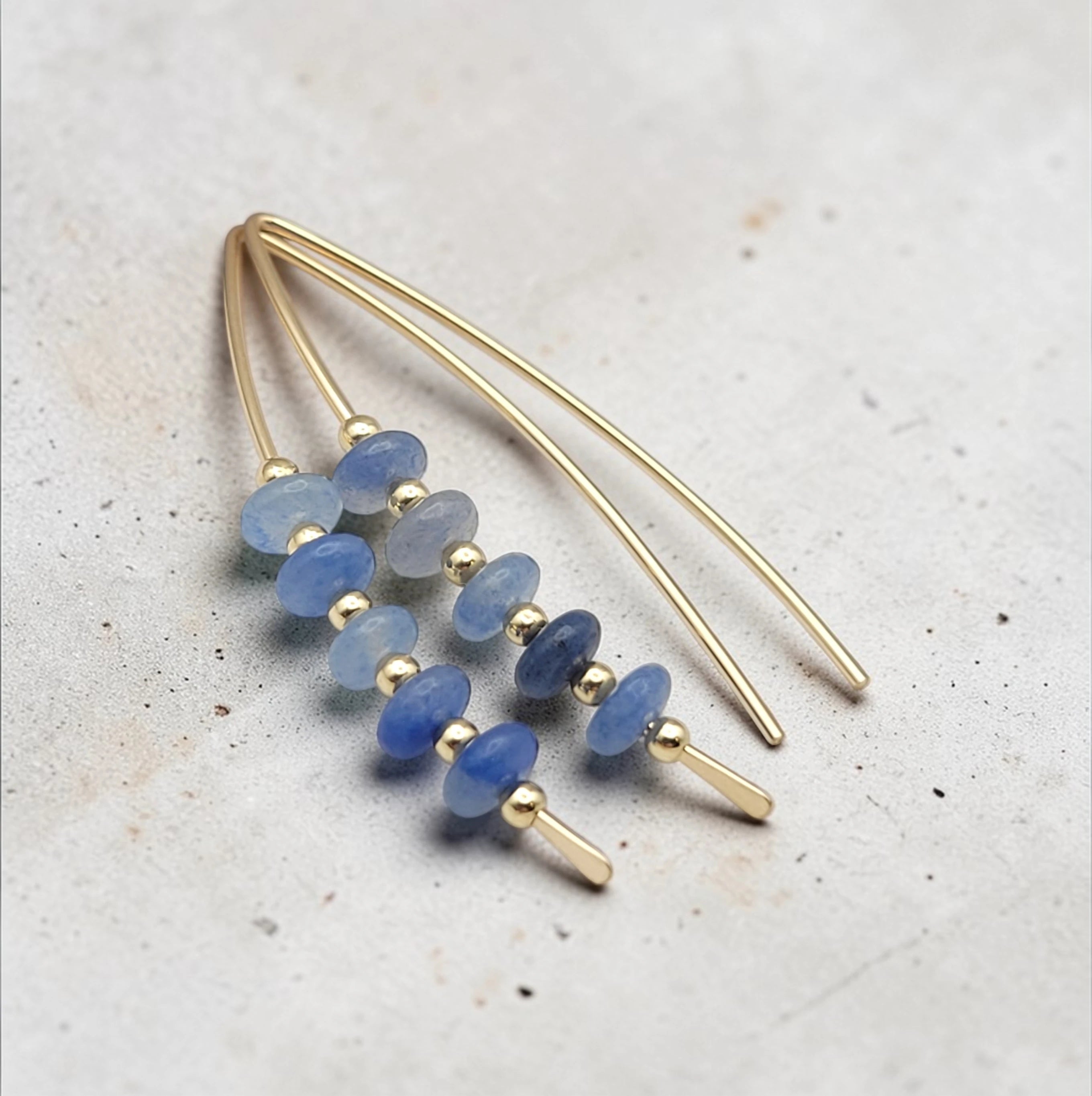 Gold and blue beaded earrings on a textured surface