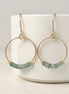 Gold hoop earrings with green aventurine beads on a white surface