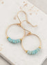 Gold hoop earrings with amazonite beads on a marble surface