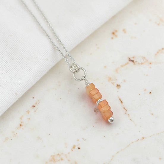 Necklace with peach-colored beads on a marble surface