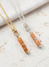 Two necklaces with peach-colored beads on a light background