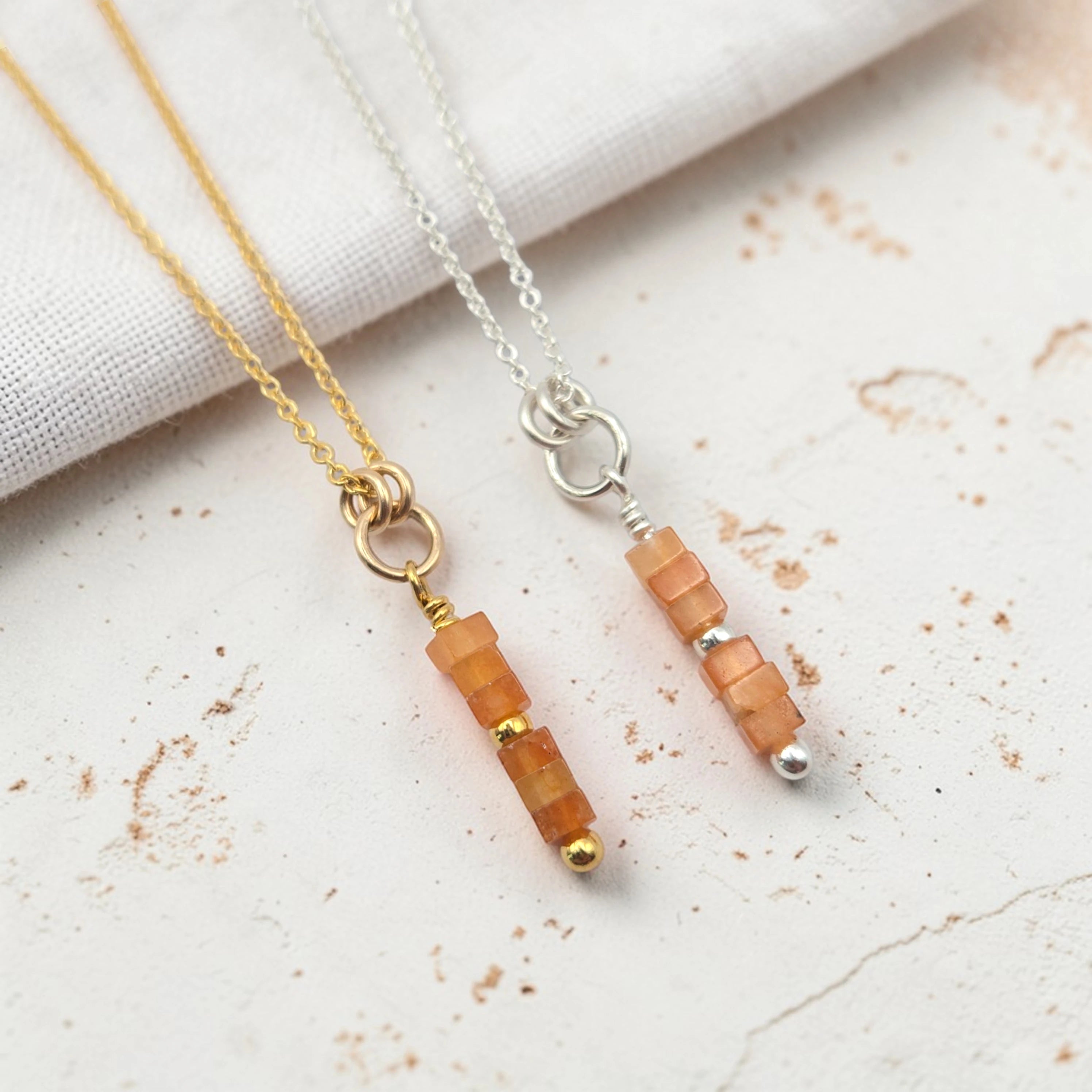 Two necklaces with peach-colored beads on a light background