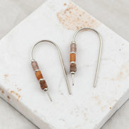 Pair of earrings with brown bead accents on a marble surface