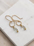 Gold earrings with clear beads on a white stone surface