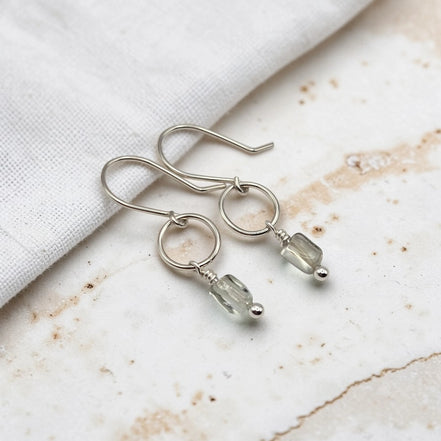 Silver earrings with gemstones on a marble surface