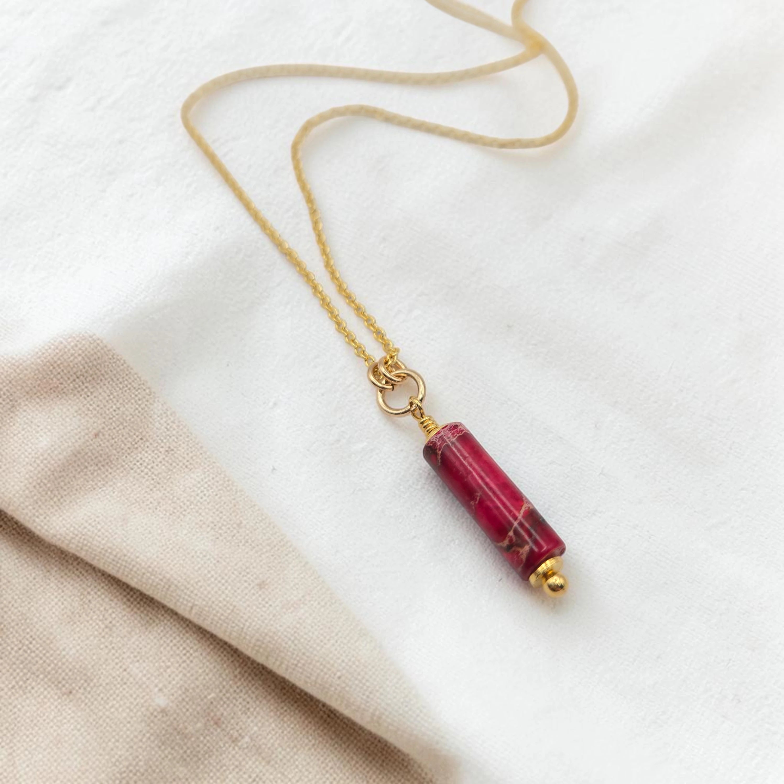 Necklace with a red cylindrical pendant on a white background