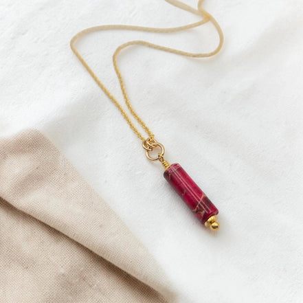 Necklace with a red cylindrical pendant on a white background