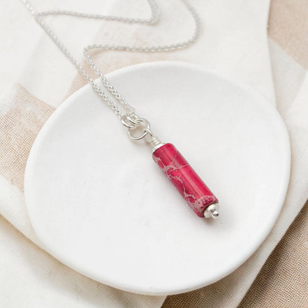 Necklace with a pink marbled pendant on a white dish