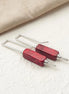 Red bar earrings with silver hooks on a light background