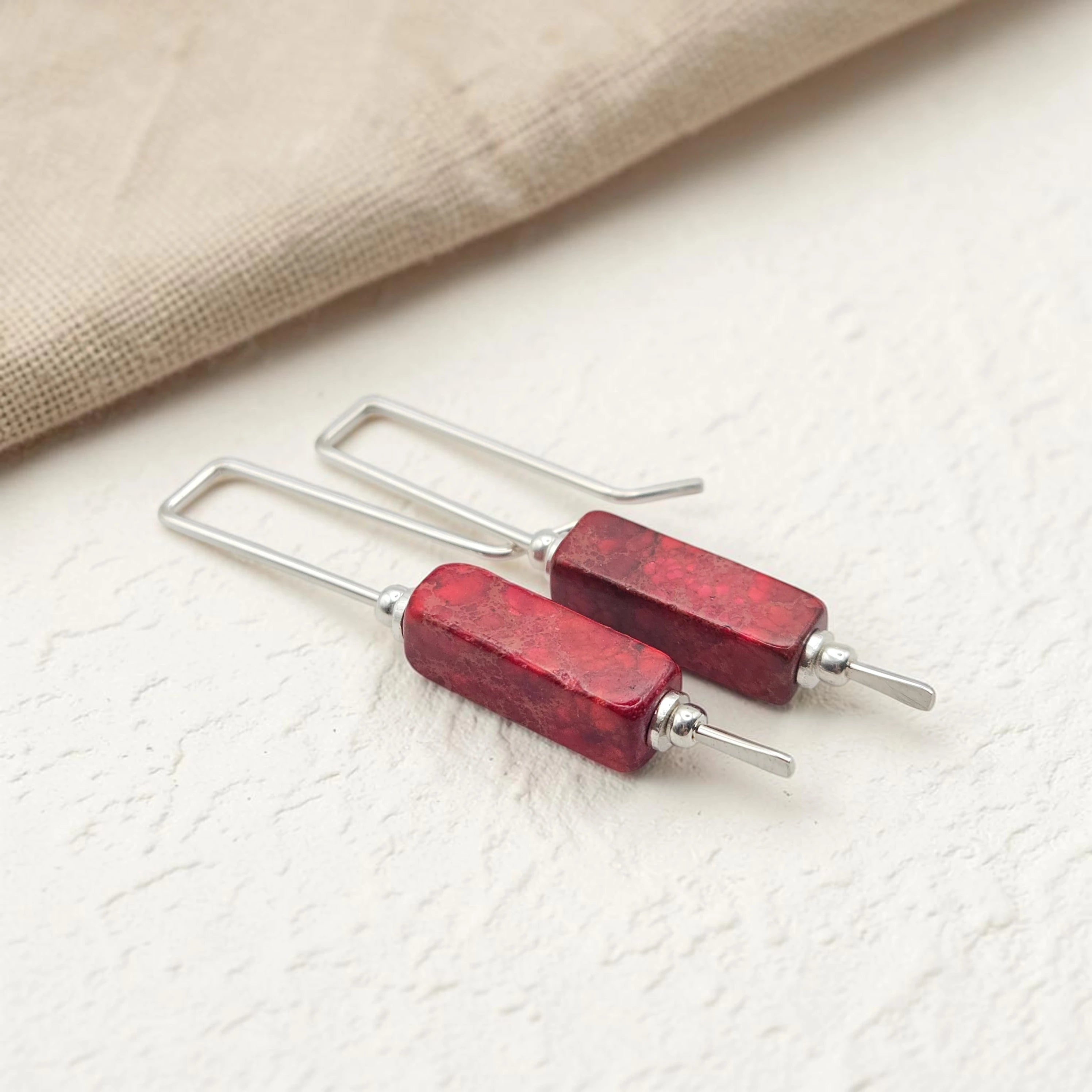 Red bar earrings with silver hooks on a light background