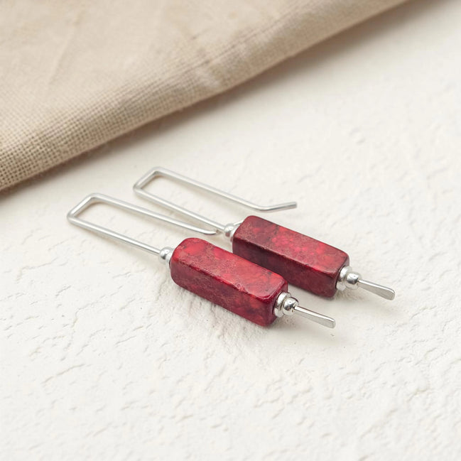 Red bar earrings with silver hooks on a light background