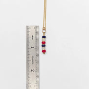 Necklace with colorful beads next to a ruler on a white background