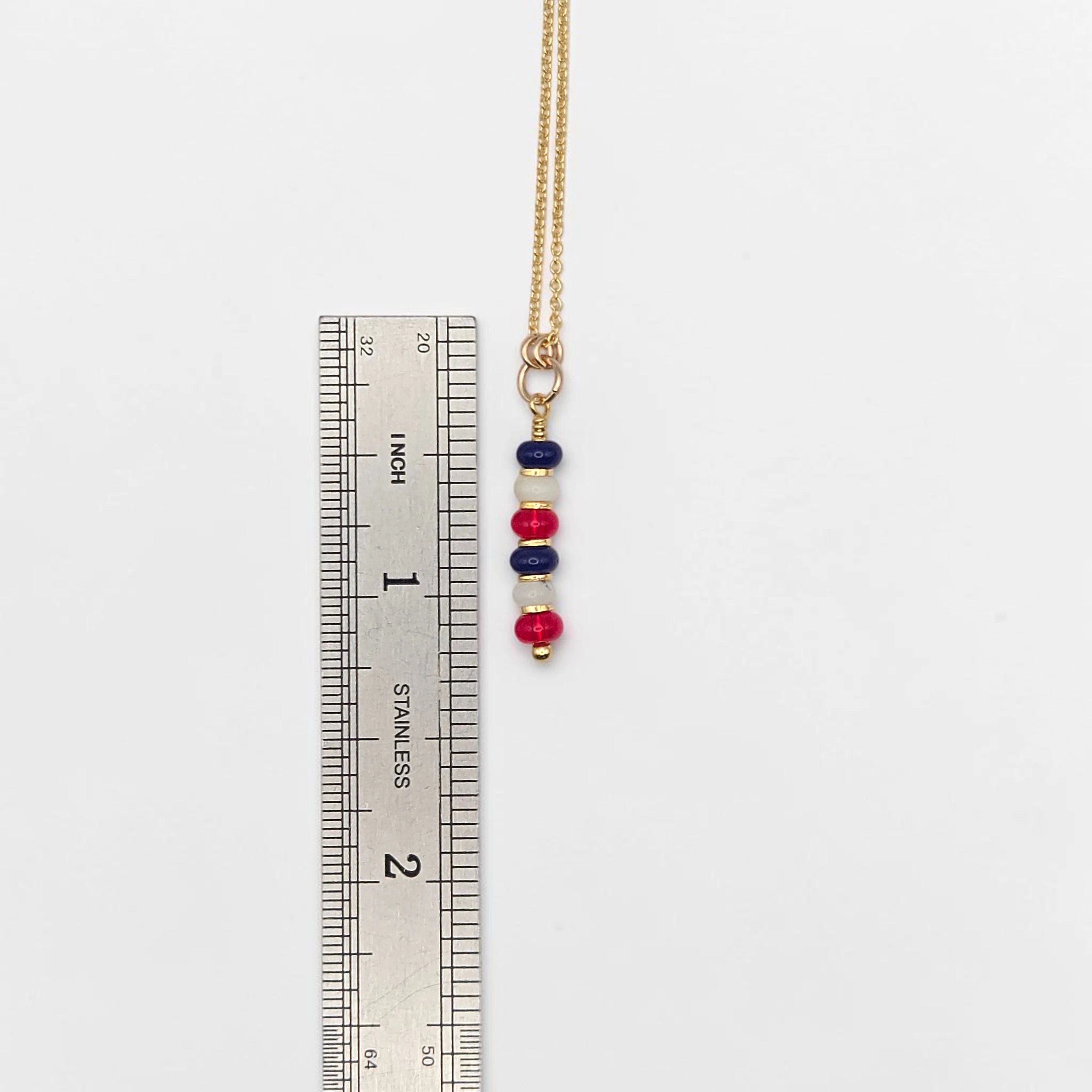 Necklace with colorful beads next to a ruler on a white background