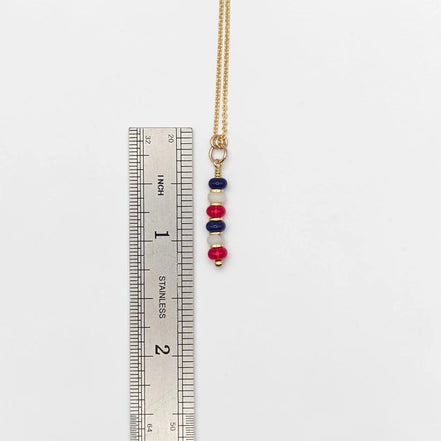 Necklace with colorful beads next to a ruler on a white background