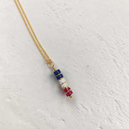 Necklace with colorful beaded pendant on a light gray background