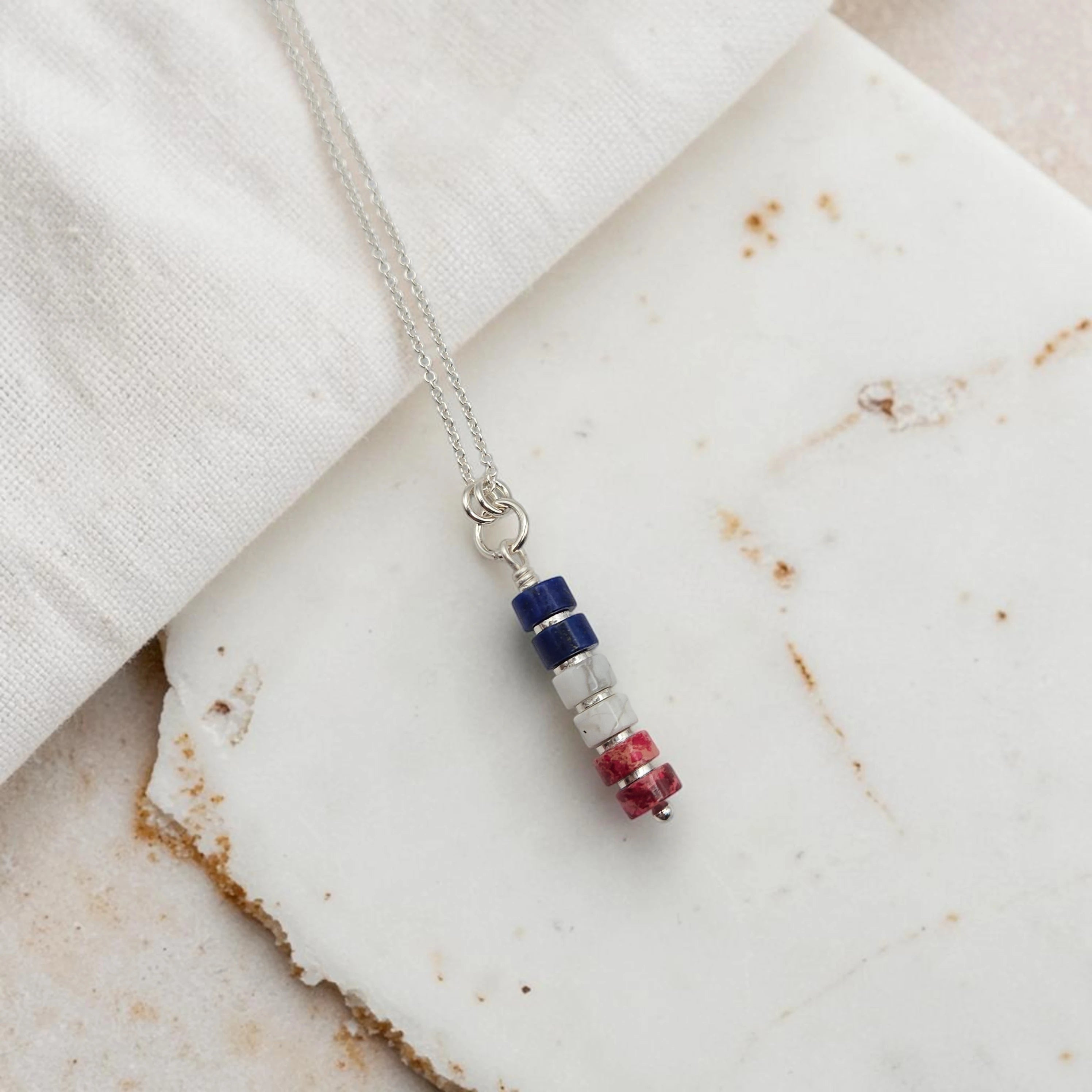 Necklace with a cylindrical pendant on a marble surface
