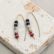 Pair of beaded red white and blue earrings on a marble surface
