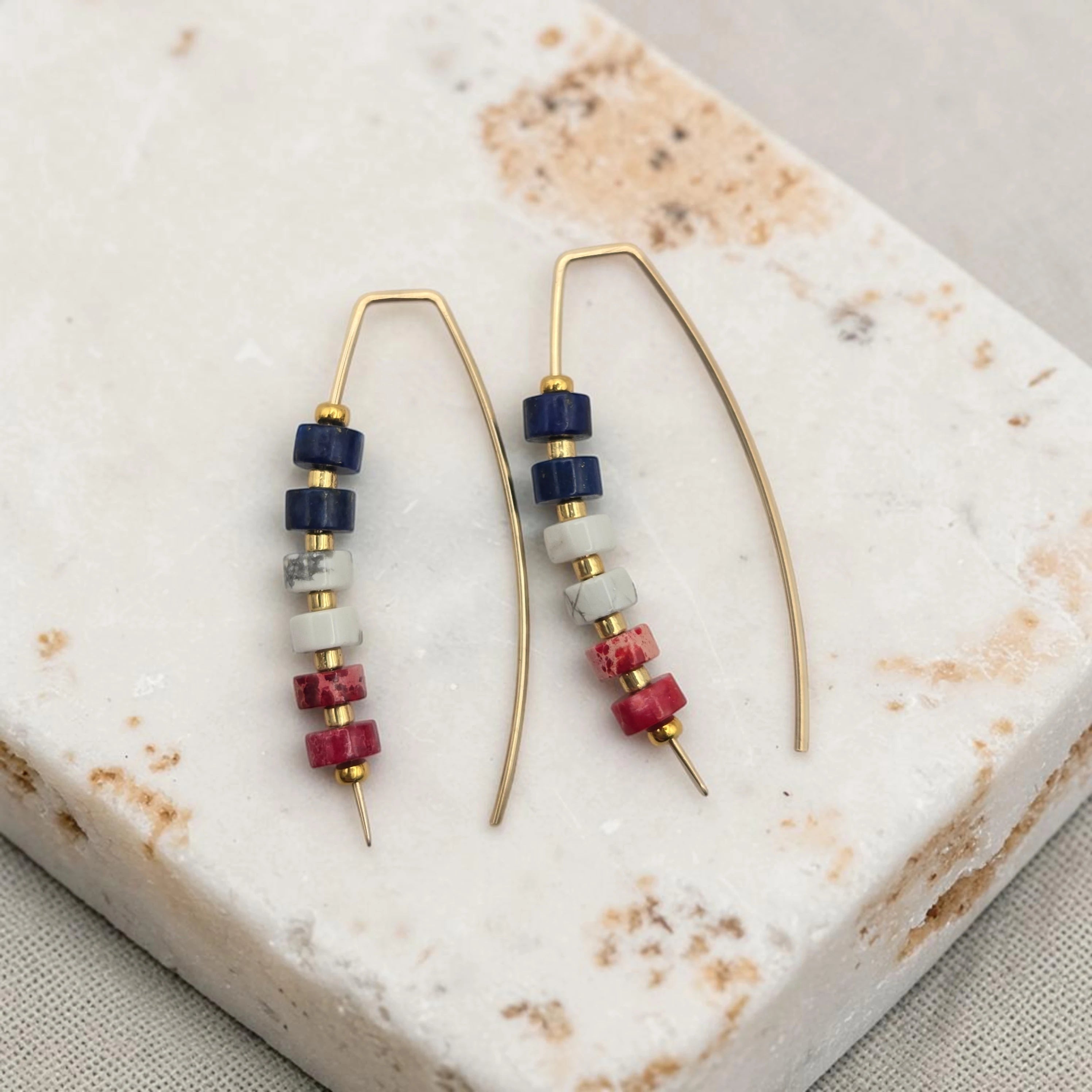 Pair of beaded red white and blue earrings on a marble surface