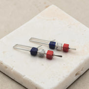 Set of earrings with red white and blue cube beads on a stone surface