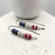 Beaded earrings with blue, red, and clear beads on a white surface.