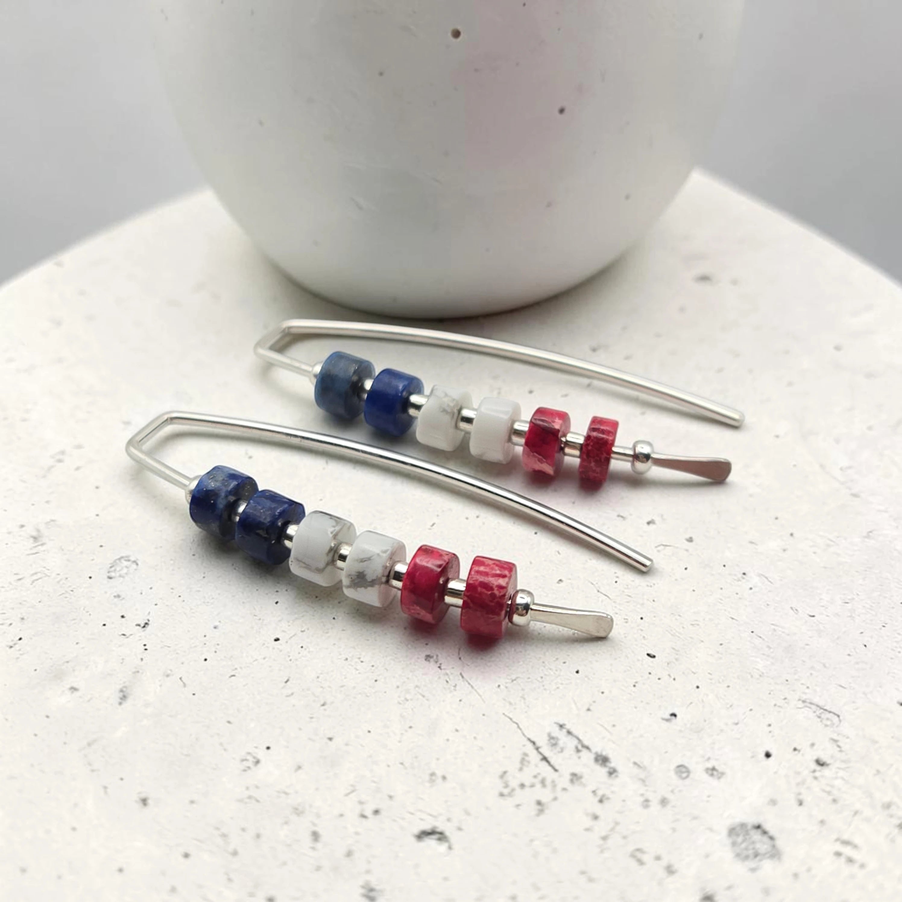 Beaded earrings with blue, red, and clear beads on a white surface.