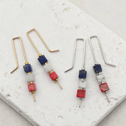 Pair of earrings with red white and blue beads on a marble surface