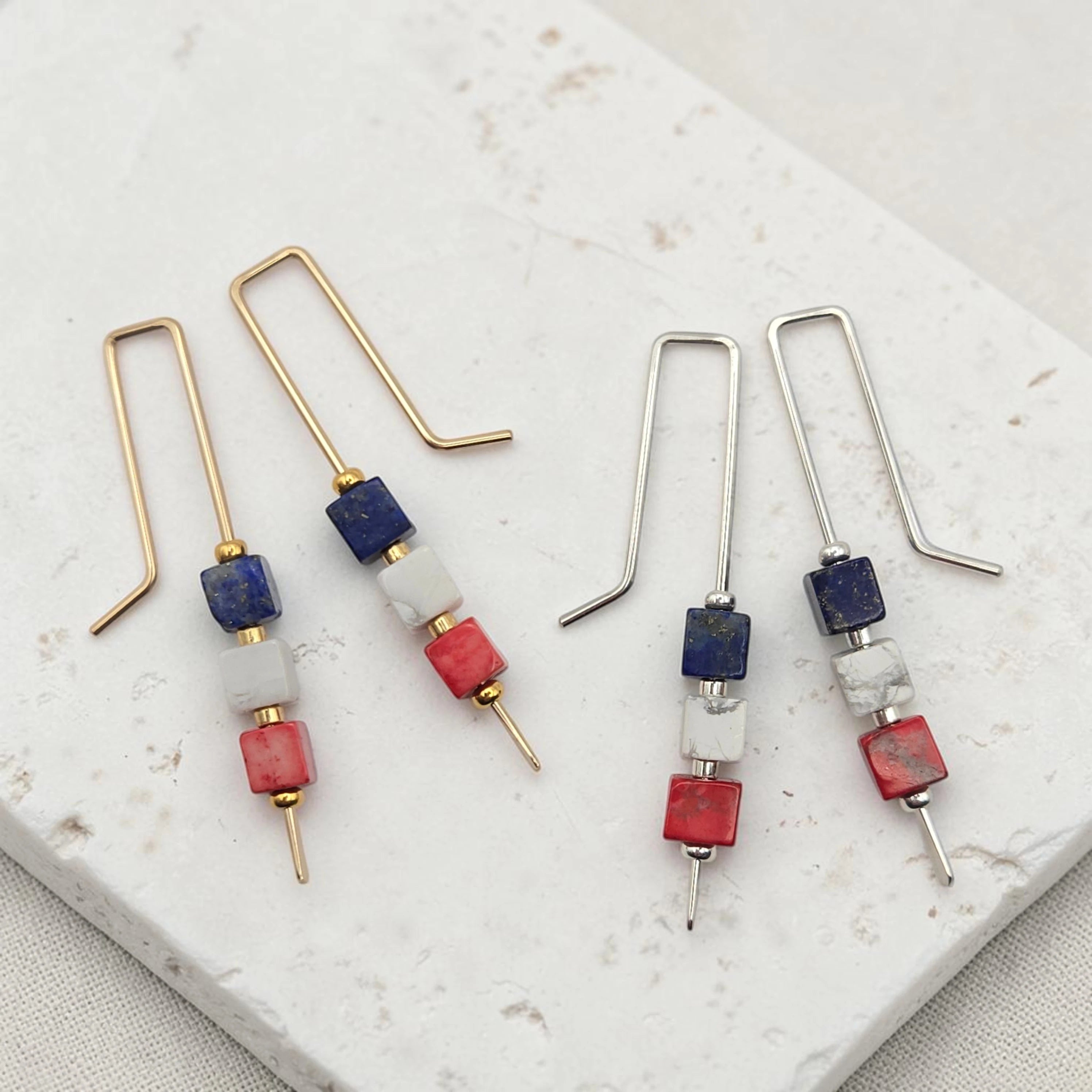 Pair of earrings with red white and blue beads on a marble surface