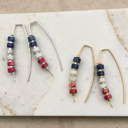Pair of red white and blue beaded earrings on a marble surface