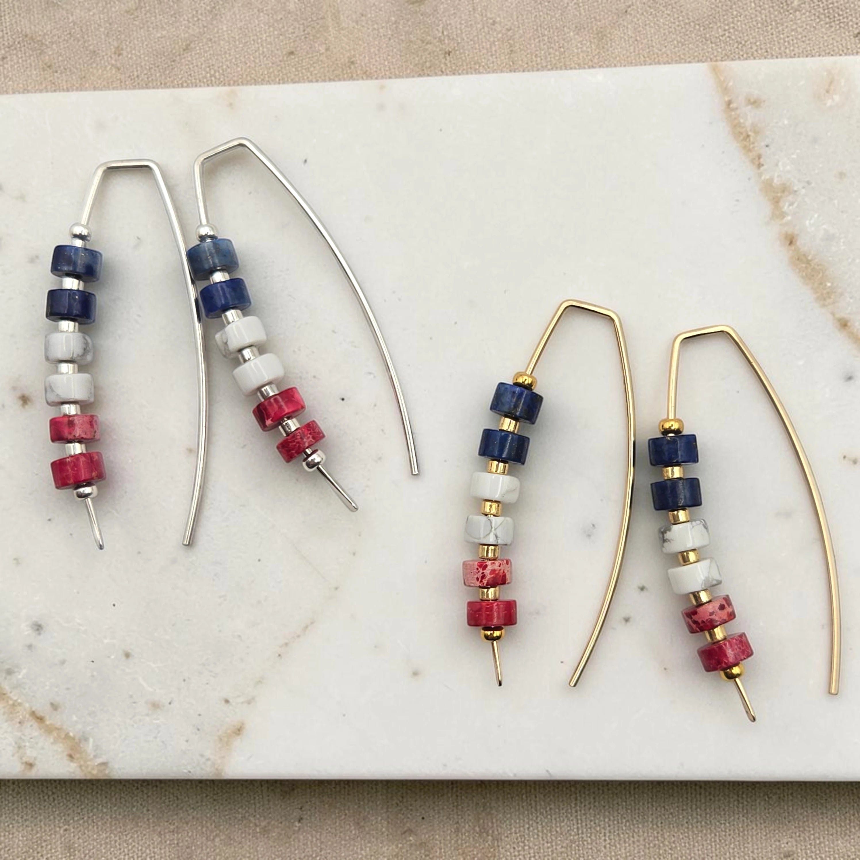 Pair of red white and blue beaded earrings on a marble surface