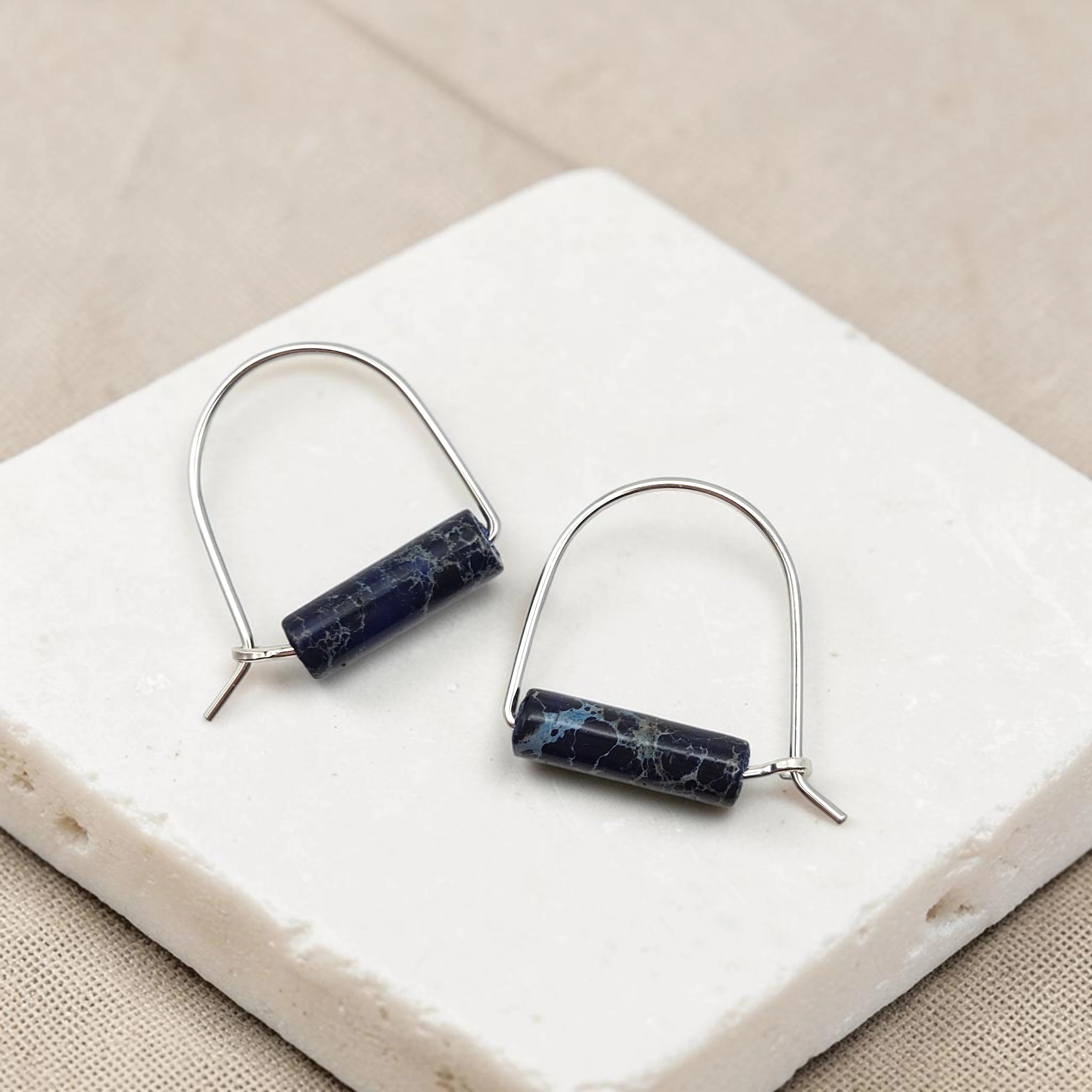 Pair of earrings with blue cylindrical stones on a white stone surface