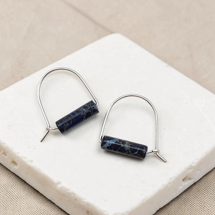 Pair of earrings with blue cylindrical stones on a white stone surface