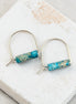 Pair of earrings with turquoise cylindrical beads on a marble surface