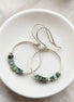 Silver hoop earrings with turquoise beads on a white dish.